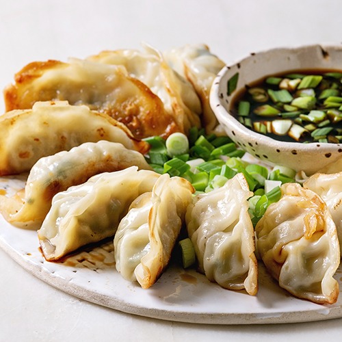 Plate of Potsticker with spring onions and bowl of soy sauce